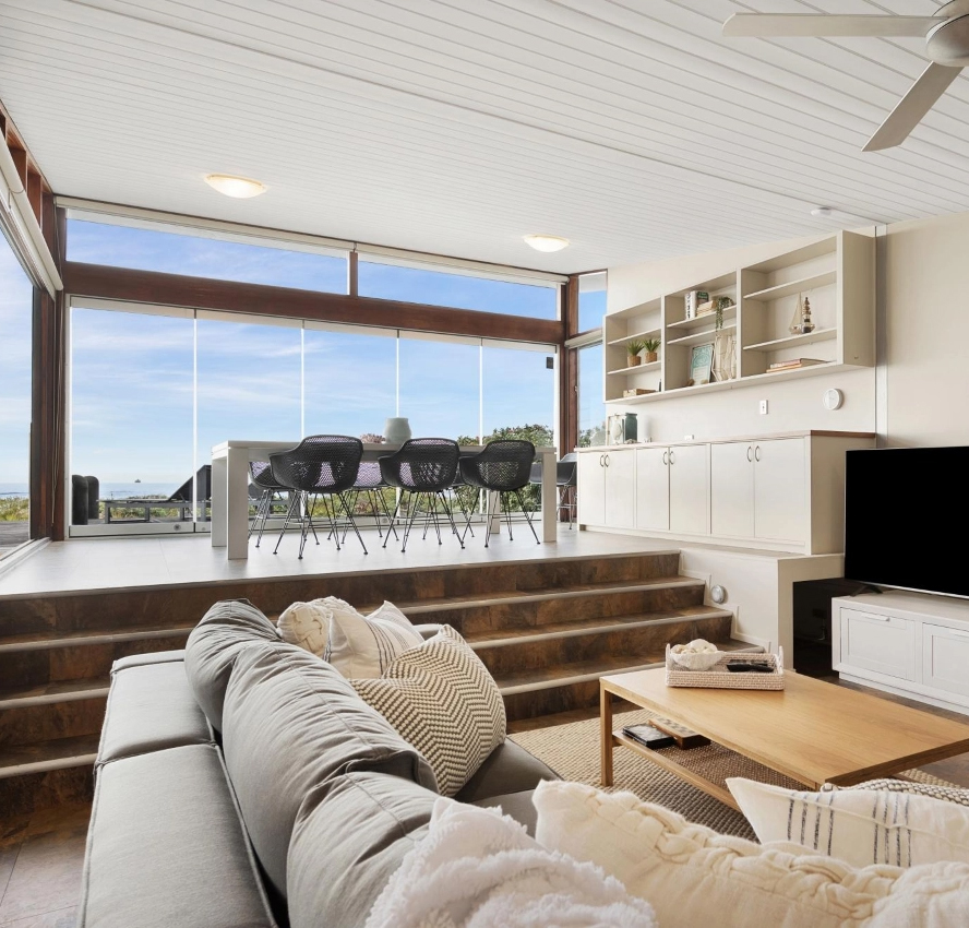 Sunken lounge looking out through full height windows to the beach